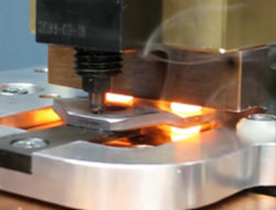Effizientes Warmnieten: Präzise Verbindungstechnik in der Fertigung Nahaufnahme eines industriellen Warmnietvorgangs. Ein erhitztes Nietwerkzeug presst ein glühendes Metallteil auf ein Werkstück, um eine sichere Verbindung herzustellen. Der Bereich um das Werkzeug leuchtet aufgrund der Hitzeeinwirkung, während leichter Rauch aufsteigt. Diese Szene zeigt die Präzision und Effizienz des Warmnietens, eine Technologie, die in der Fertigung eingesetzt wird.