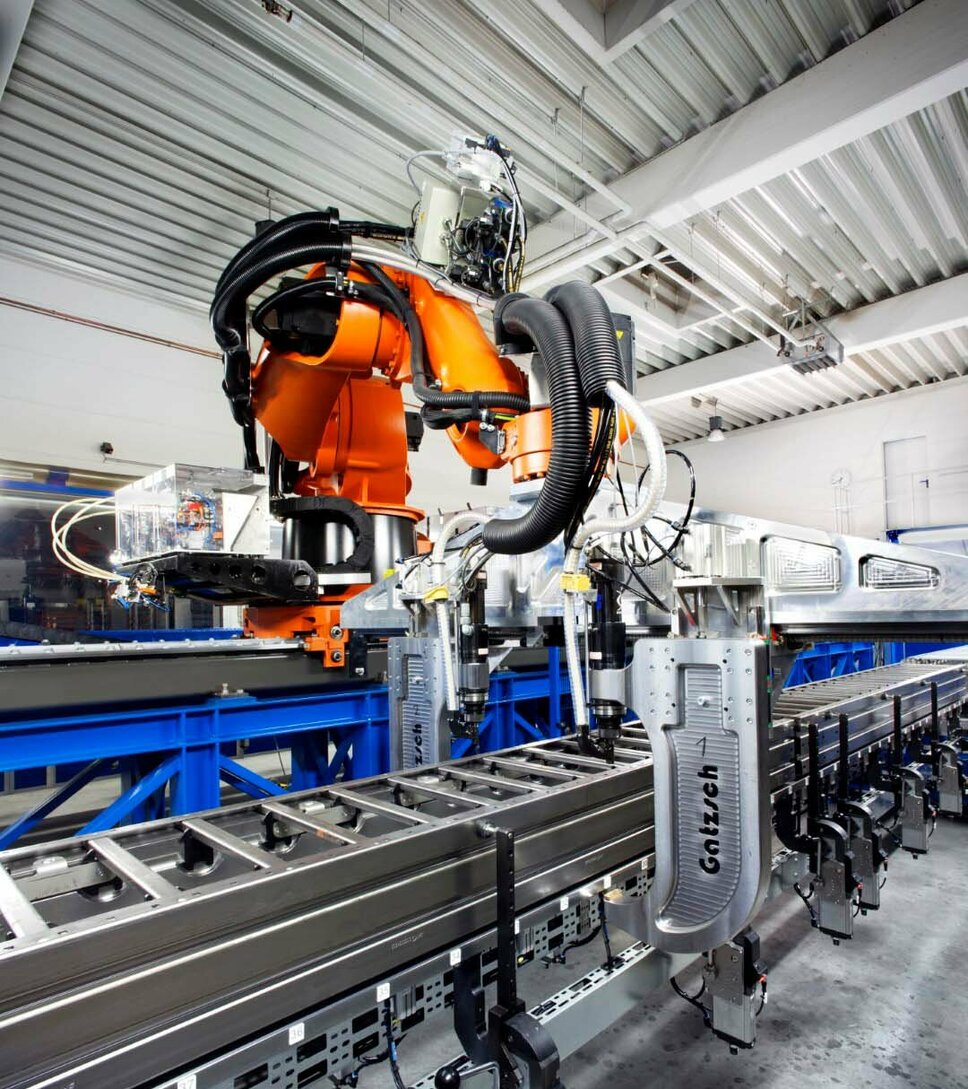 Ein moderner Industrieroboter in einer Produktionshalle, der an einer automatisierten Fertigungslinie arbeitet. Der Roboter führt Nieten und Clinchen durch, um Metallkomponenten präzise miteinander zu verbinden. Die Maschine, von der Firma Gatzsch Schweißtechnik,  ist an einer Förderanlage befestigt und befindet sich in einer hellen, industriellen Umgebung.